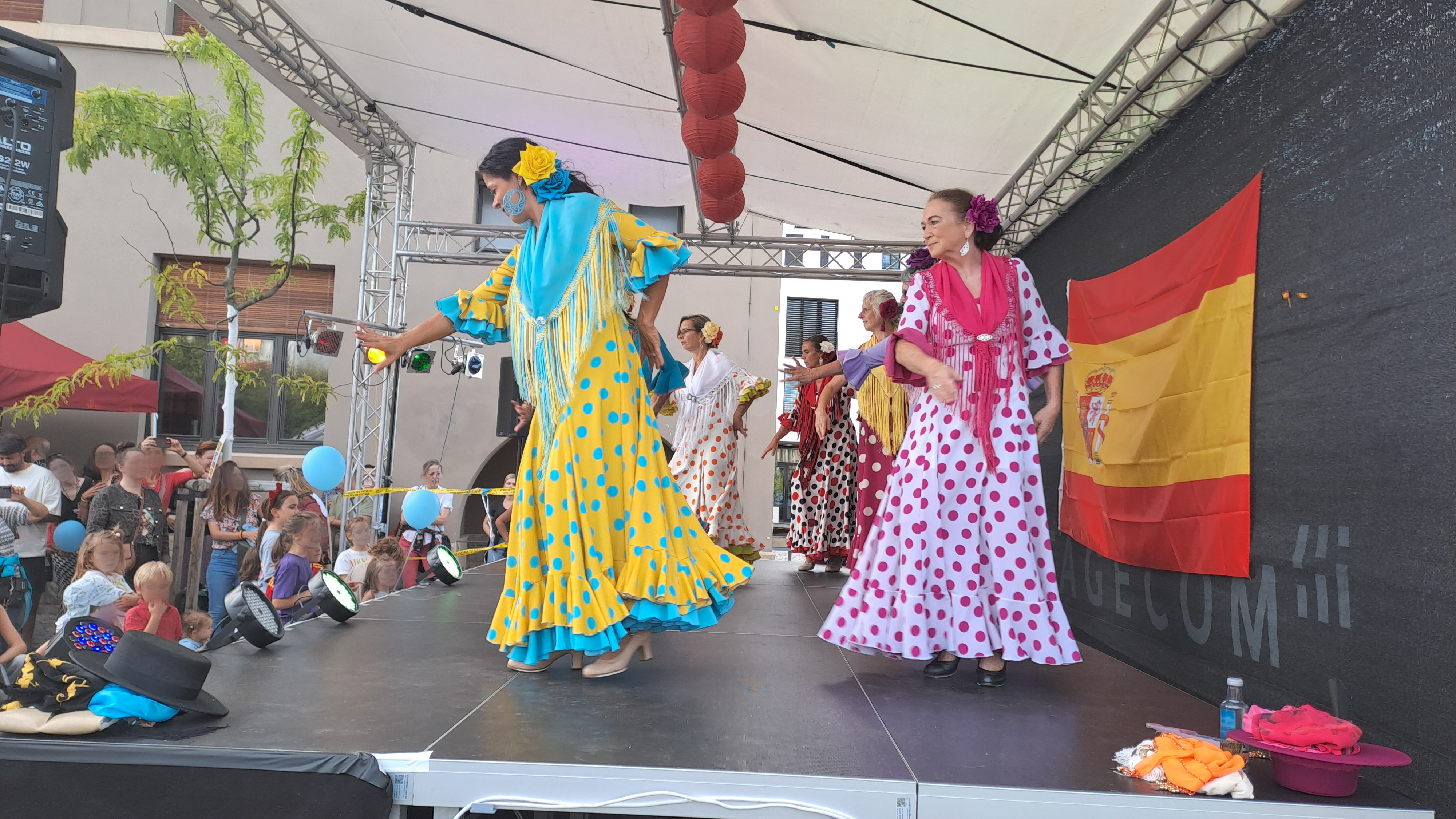 Group of Spanish Flamenco dancers performing on a stage in front of several "Fiesta Española Basel" attendees